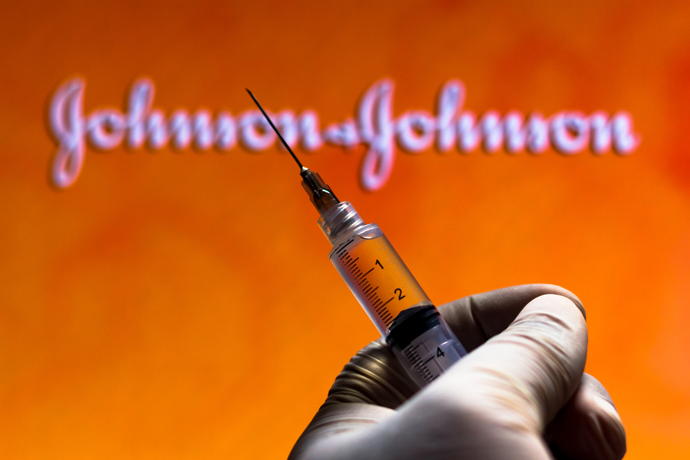 November 13, 2020, Brazil. In this photo illustration the medical syringe (coronavirus vaccine) is seen with Johnson and Johnson company logo displayed on a screen in the background.