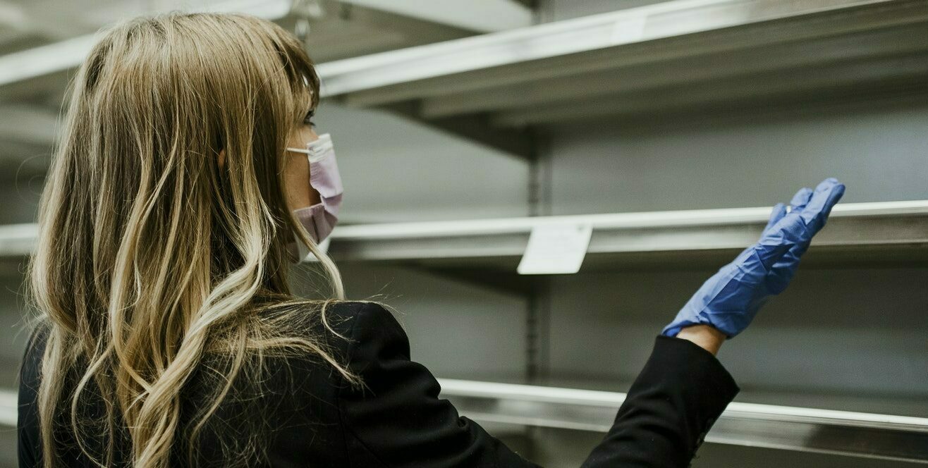 Woman with empty shelves in a supermarket during coronavirus pan